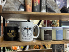 Coffee mugs and candles inspired by fourth wing book series on a wood shelf.