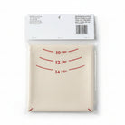 A packaged set of three beige canvas dishcloths with red printed measurement markings (10 in, 12 in, 14 in) on a gray concrete floor. The top cloth shows its white paper header card with a barcode and washing instructions.
