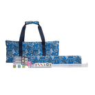 A Mahjong set displayed on a clean white background, featuring a blue patterned carrying bag with dark navy handles, a matching rolled case, and several tiles laid out in front.