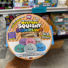 A hand wearing a brown knit sleeve holds a round dumpling steamer container with packaging that states: 'The Original Viral Mystery Squishy Dumpling' Rare Glitter Edition. The packaging features colorful cartoon dumpling graphics.